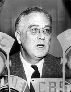 Photograph President Franklin Delano Roosevelt in front of microphones of U.S. radio networks.