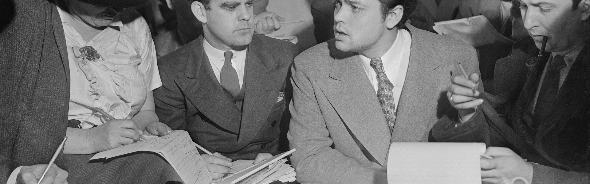 Photo of Orson Welles meeting with reporters in an effort to explain that no one connected with the War of the Worlds radio broadcast had any idea the show would cause panic. Future first Voice of America (VOA) director John Houseman was the producer of the War of the Worlds fake entertainment newscast.